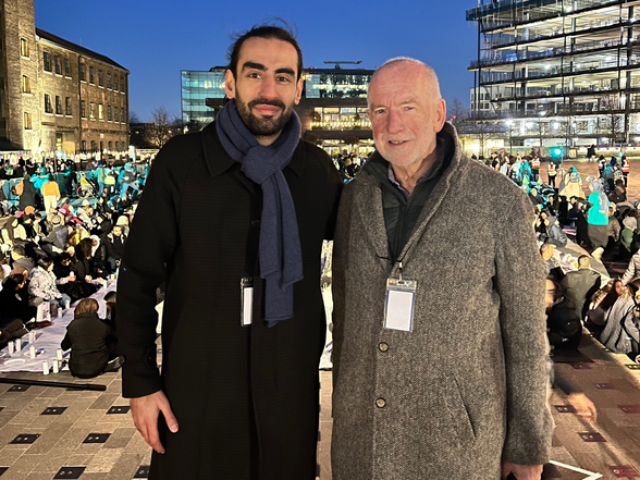 Two men taking a picture wearing coats.